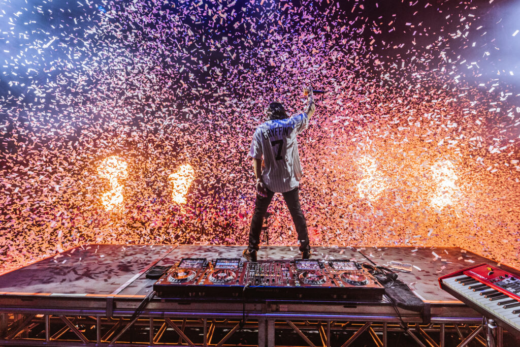 Gryffin stands with his back to the camera and facing the crowd as confetti rains down on the crowd.