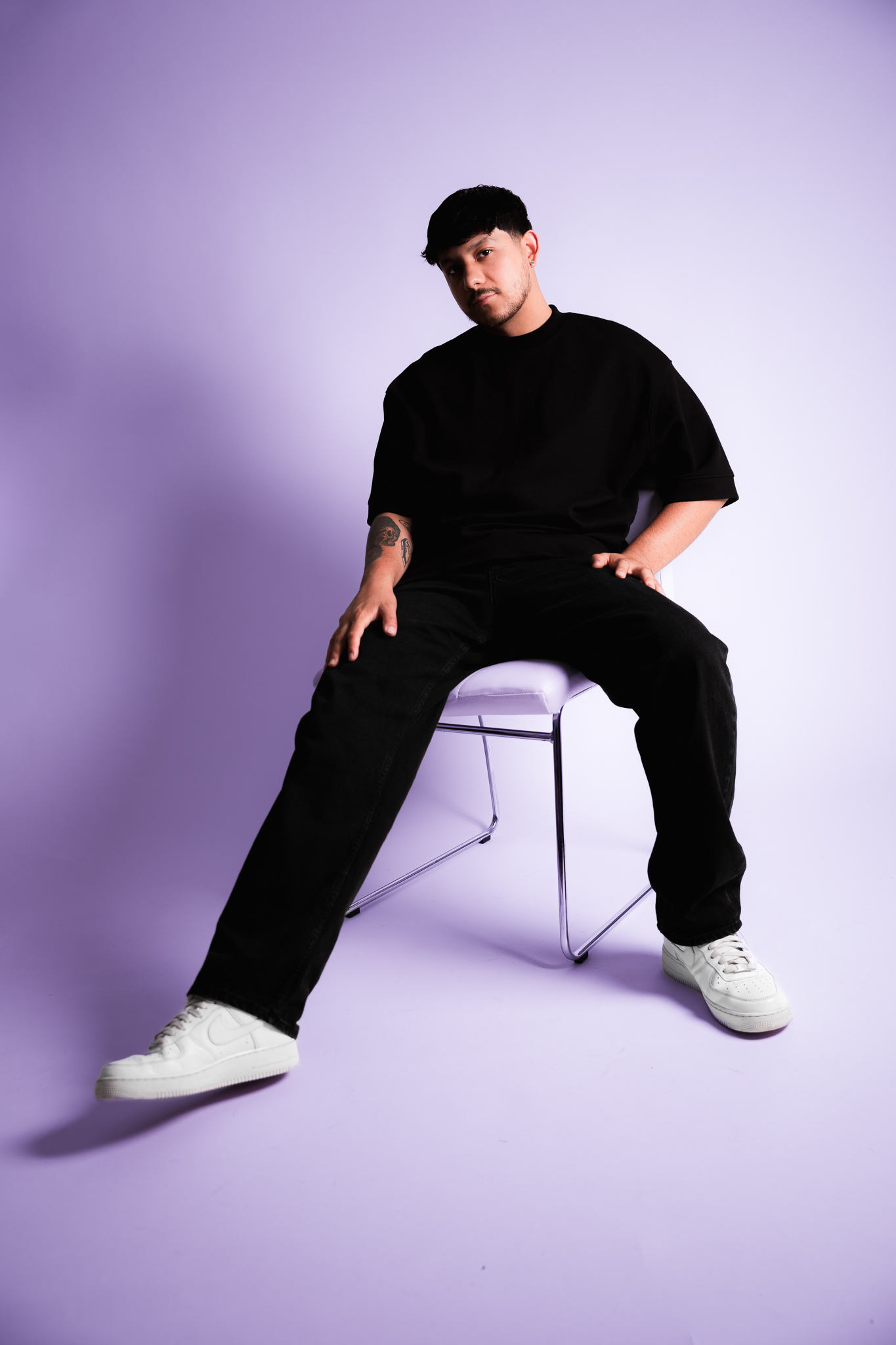 YDG wearing all black photographed while sitting in a chair