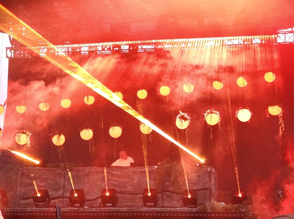 Red lights drop from the stage with lasers shooting across the park.